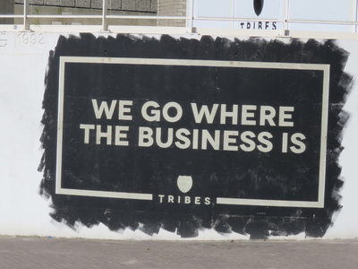 838252 Afbeelding van de muurreclame 'We go where the business is' van Tribes (huur flexplekken e.d., Leidseveer 2), op ...